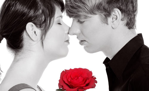 赤いバラを持つ男性と目を閉じて近づく女性